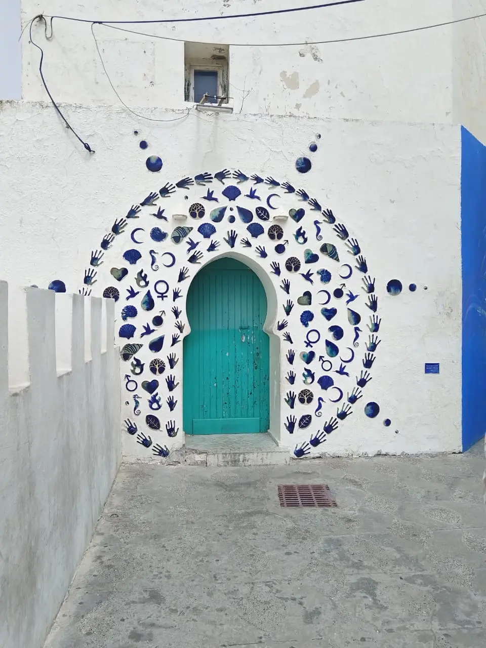Whitewashed medina alley with a turquoise arched door